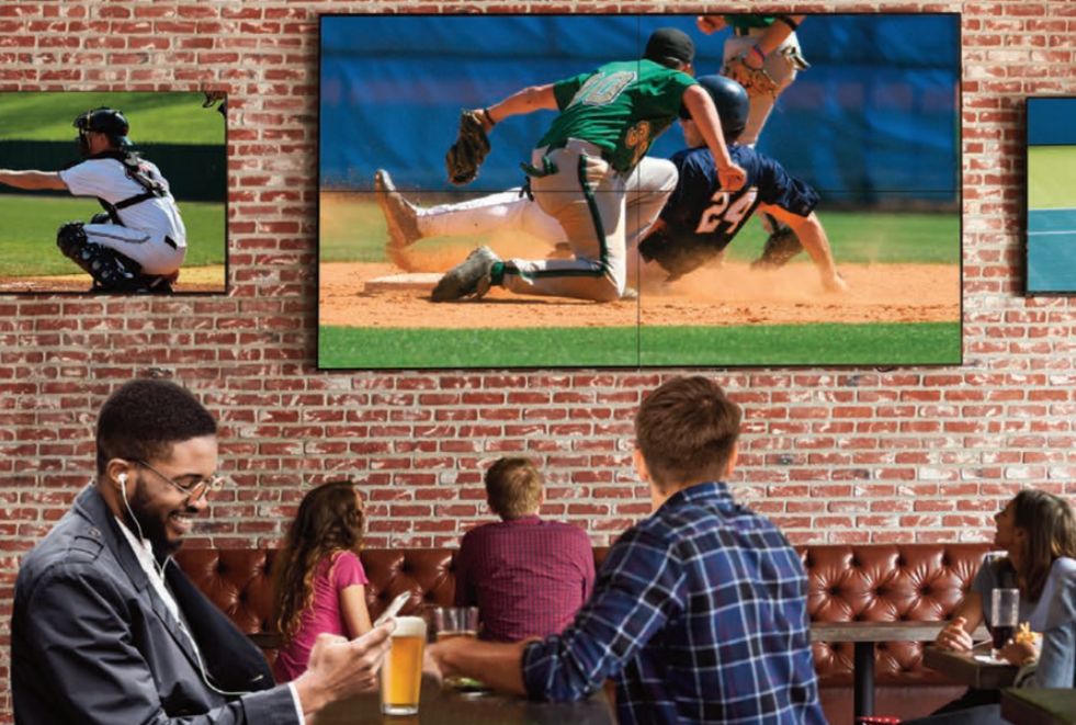commercial iptv Crowd watching a live sports event on multiple TVs in a bar, all synchronized through a commercial IPTV system.